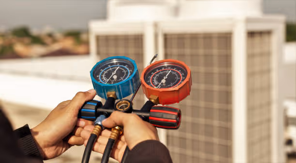 Technician holding blue and red pressure gauges for HVAC system