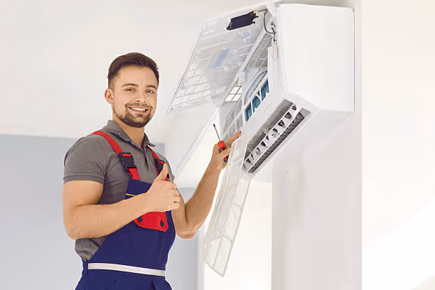 Technician repairing and cleaning an air conditioning unit with a smile