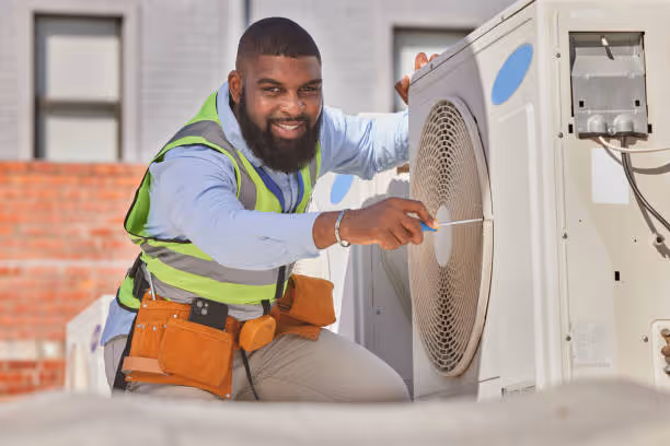 Technician in safety vest repairs air conditioning unit outdoors