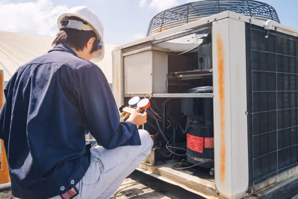 Technician in white hard hat checking industrial air conditioning unit
