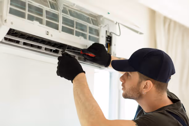 Technician installing or repairing wall-mounted air conditioning unit