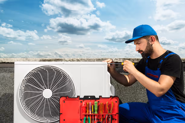 Technician repairing air conditioner unit on rooftop with tools