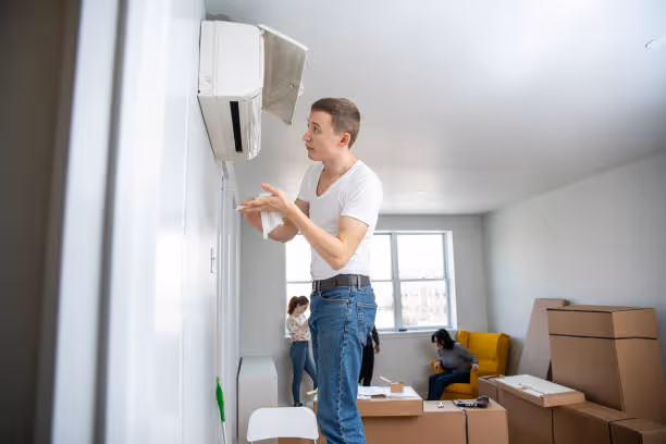 Person adjusting wall-mounted air conditioner during home move