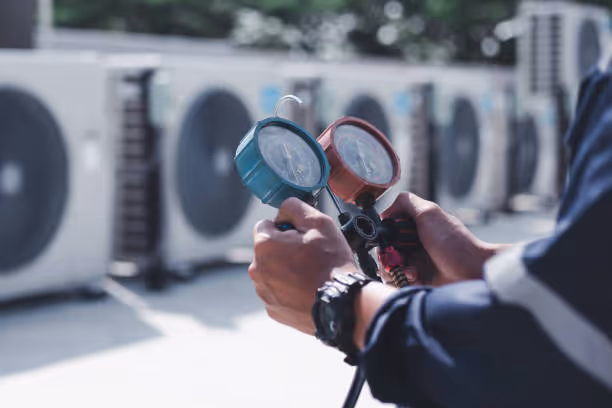 Technician checking air conditioning units with pressure gauges