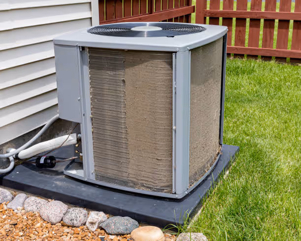 Outdoor air conditioning unit sitting on concrete pad next to green lawn