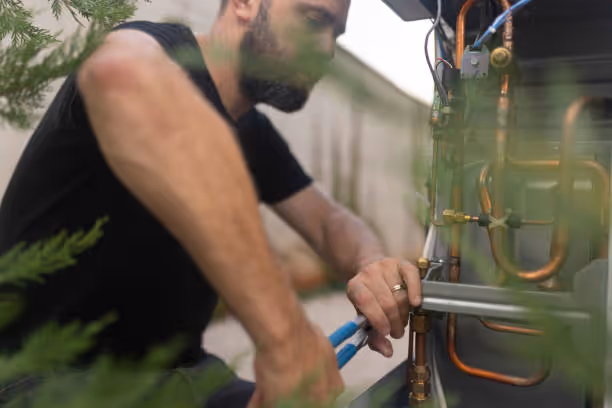 Person adjusting industrial equipment with blue-handled pliers outdoors