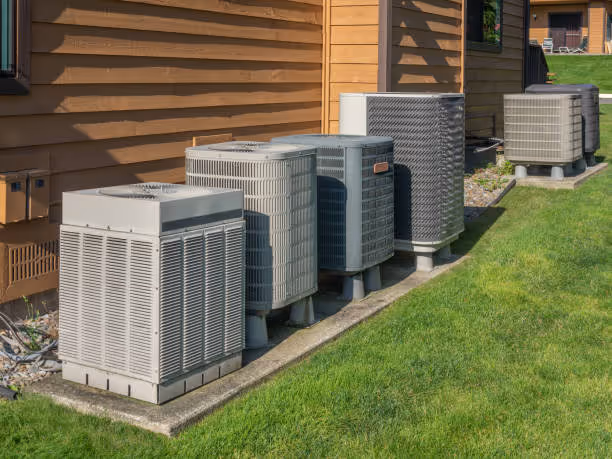 Multiple air conditioning units lined up next to wooden house exterior