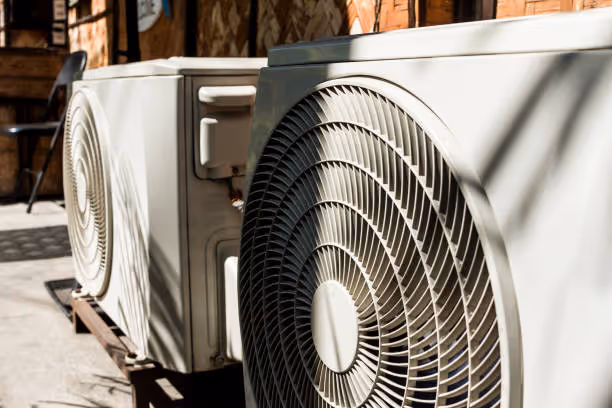 White air conditioning unit with large fan mounted on brick building exterior
