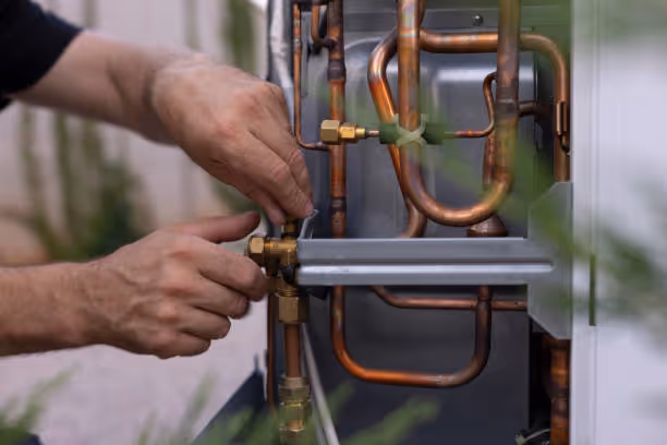 Hands adjusting copper pipes and connections on a mechanical system