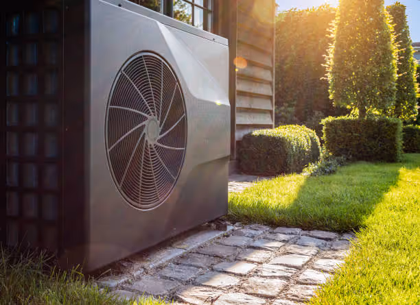 Heat pump installed outside modern house with manicured garden and sunlight