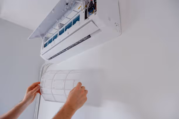 Hands installing or adjusting a white wall-mounted air conditioning unit