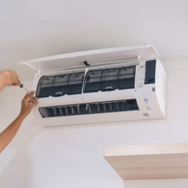Hand adjusting white wall-mounted mini-split air conditioning unit