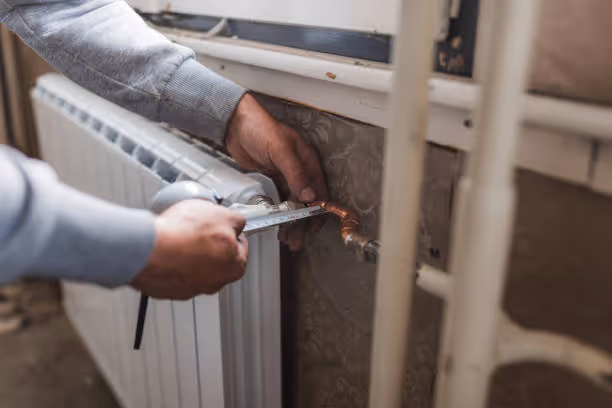 Hands adjusting or repairing a home radiator heating system