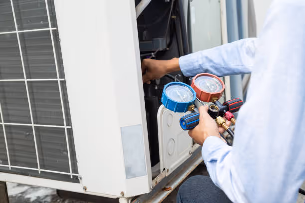 Technician checking air conditioning unit with pressure gauges