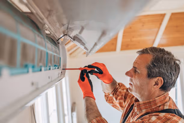 Worker in red gloves installing or repairing air conditioning unit