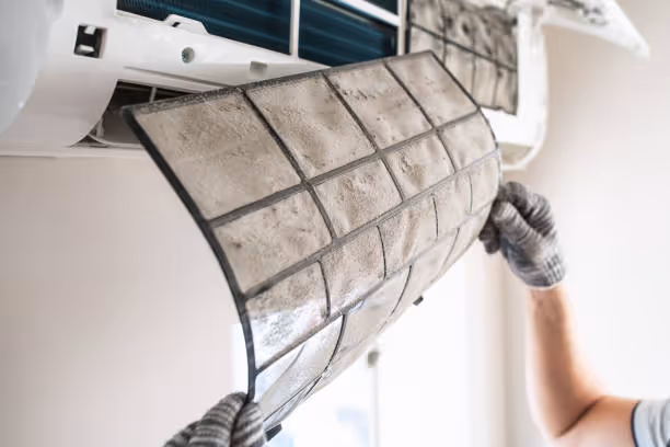 Air conditioning filter being cleaned or replaced by gloved hand