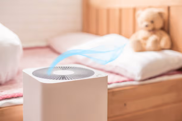 Air purifier with blue airflow near teddy bear on child's bed