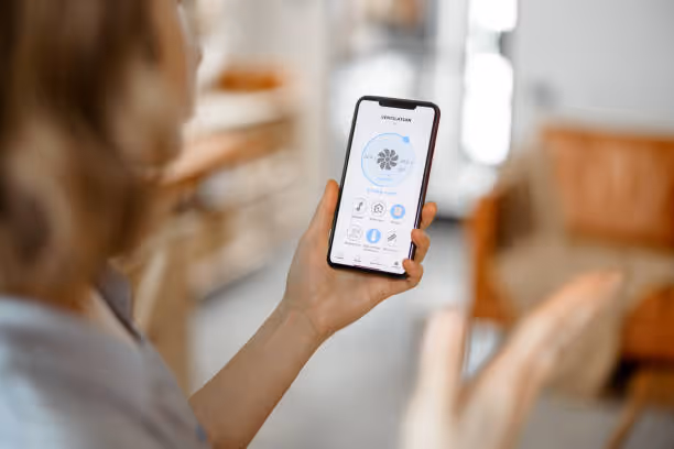 Person holding smartphone with smart home app controlling household devices