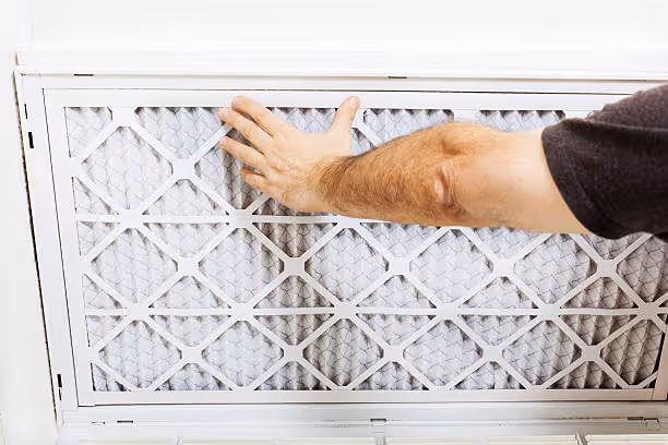 Hand replacing dirty air filter in home HVAC system
