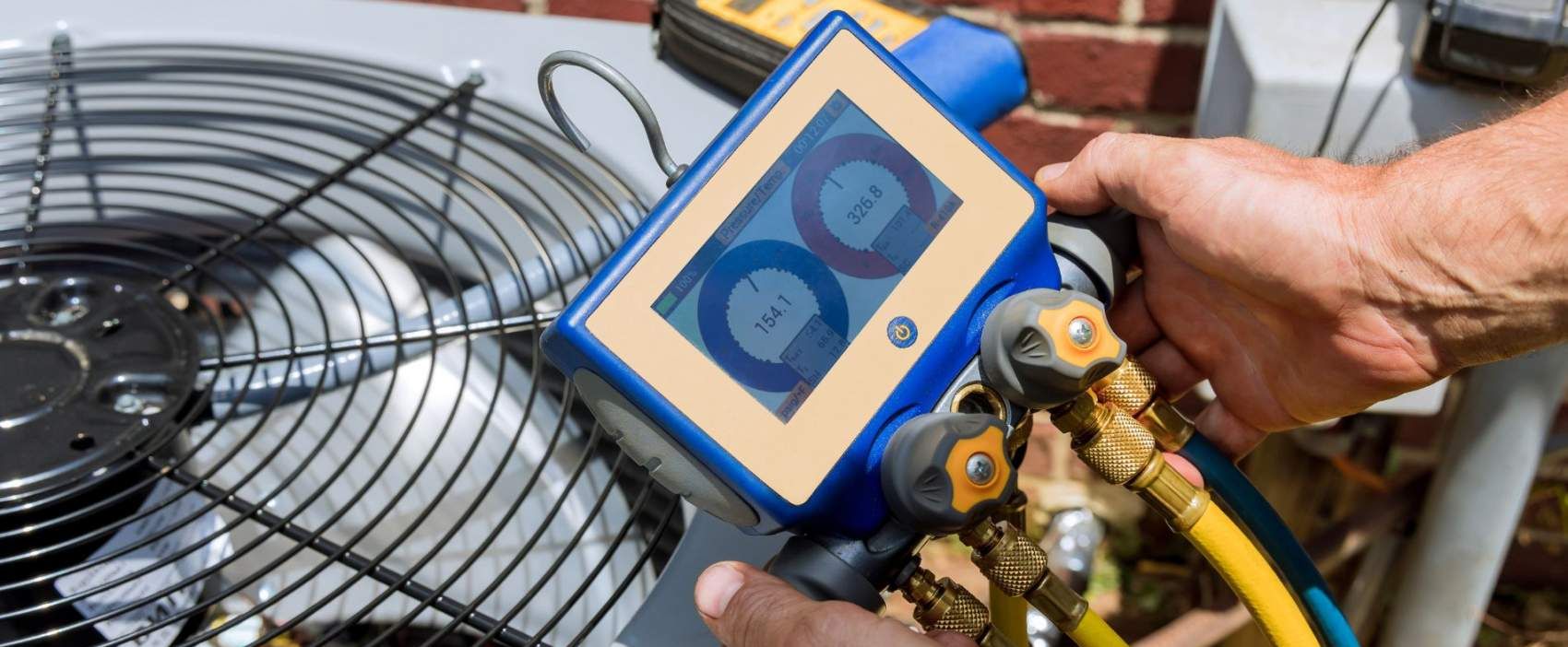 Technician using digital manifold gauge to check HVAC system pressures