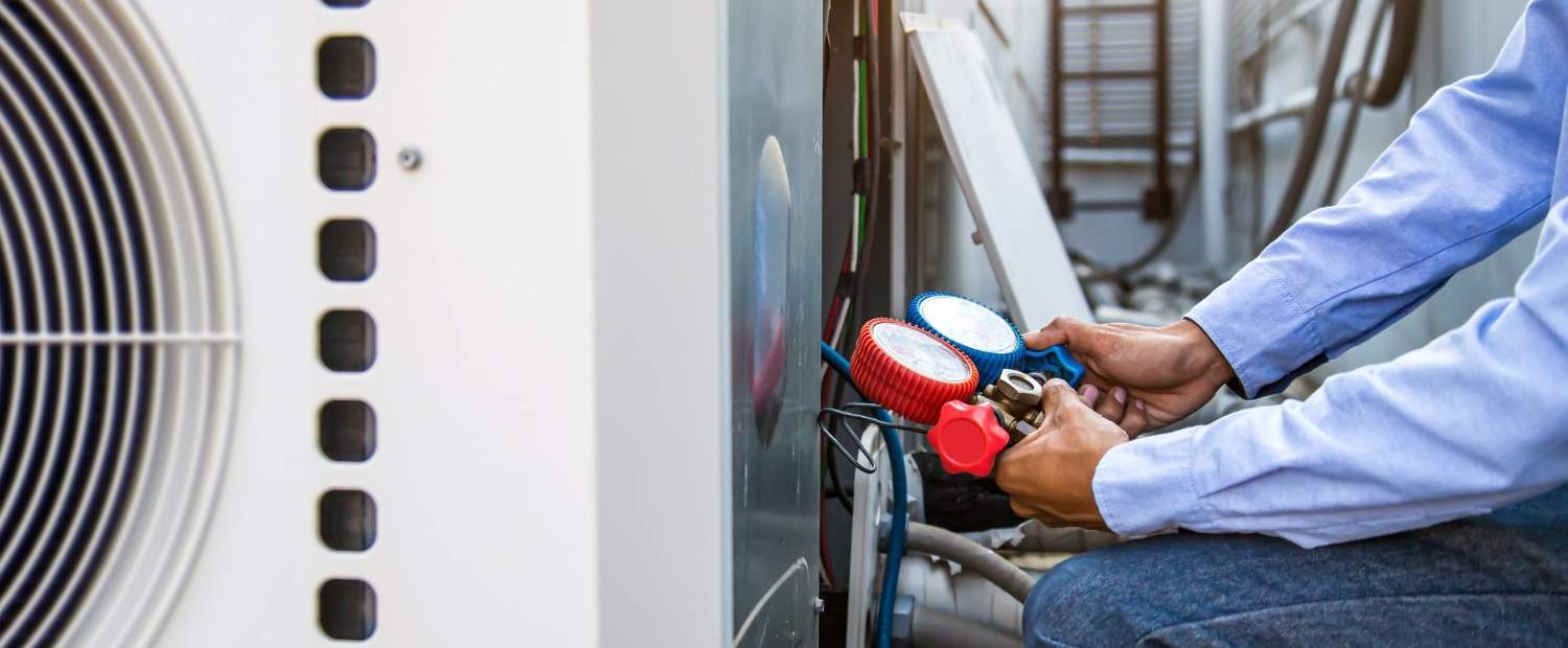 Technician checking air conditioning unit with pressure gauge manifold