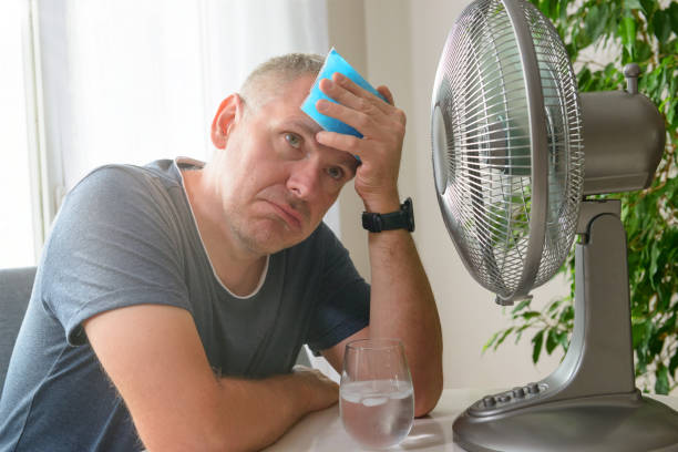 Person feeling hot, cooling off with ice pack in front of fan