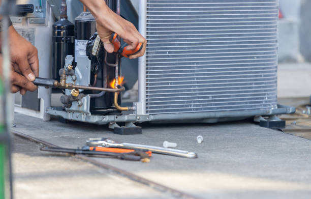 Technician repairing air conditioning unit with tools and copper pipes