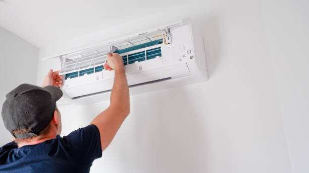 Technician installing or adjusting wall-mounted air conditioning unit