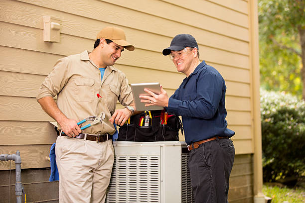 Two technicians discussing HVAC maintenance near outdoor air conditioning unit
