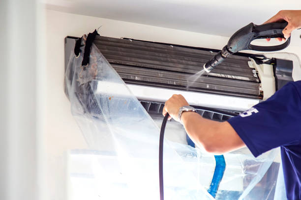 Technician cleaning air conditioning unit with high-pressure water spray