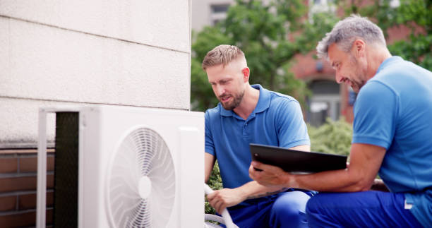 Two technicians checking an outdoor air conditioning unit together
