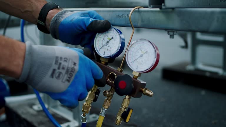 Gloved hand adjusting pressure gauges on industrial equipment manifold