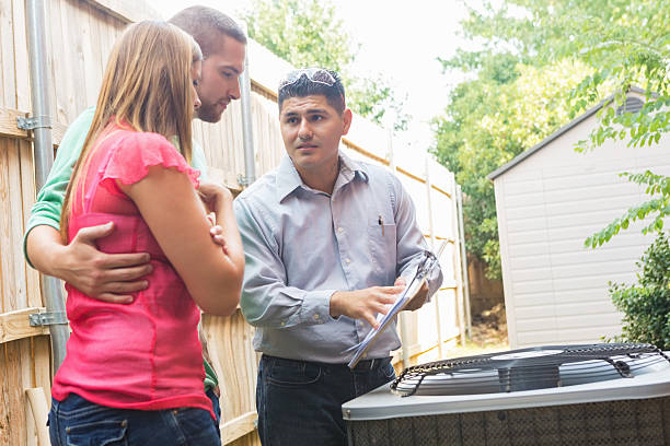 HVAC technician discussing air conditioning unit with concerned homeowners