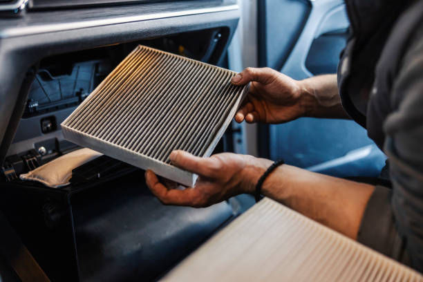 Hands removing a car cabin air filter from vehicle dashboard