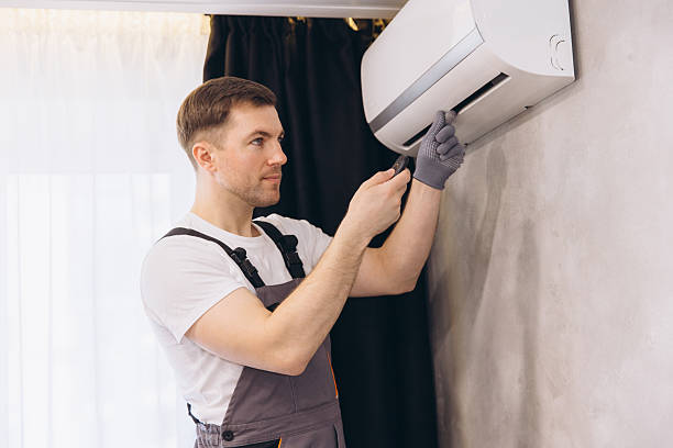 Technician installing wall-mounted air conditioning unit in home