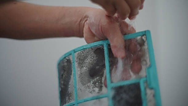 Hand holding teal-framed window with condensation and blurry view