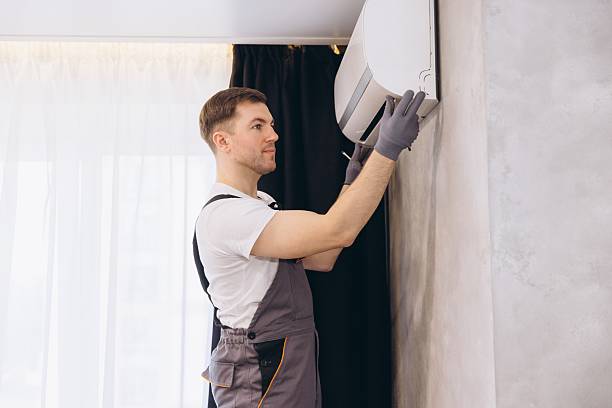 Worker in overalls smoothing wallpaper on white wall with gloved hands