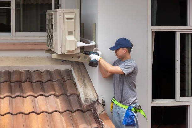 Technician installing or repairing air conditioning unit on tiled roof