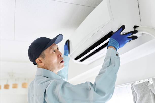 Technician in blue gloves installing or repairing a wall-mounted air conditioner