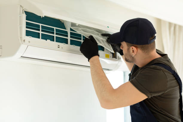 Technician installing or repairing a wall-mounted air conditioning unit