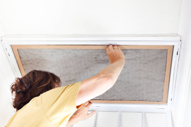 Person in yellow shirt opening an attic or ceiling access panel