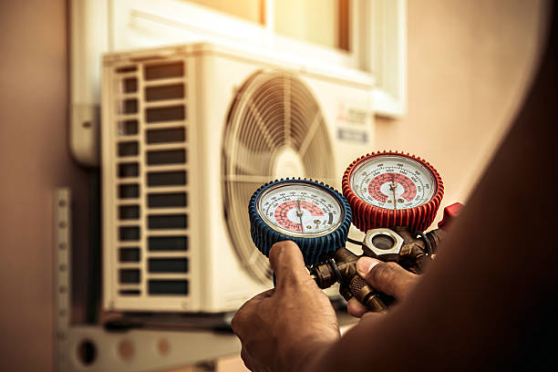 Technician checking air conditioning unit with pressure gauges