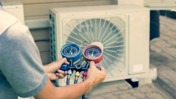 Technician checking air conditioning unit with pressure gauges