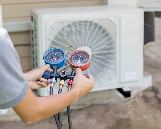 Technician checking air conditioning unit with pressure gauges