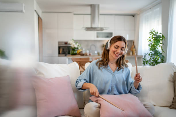 Woman listening to music with headphones, relaxing on couch at home