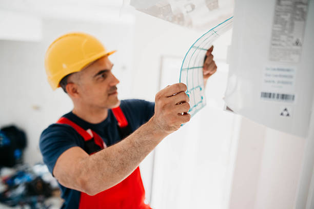 Construction worker in hard hat examining blueprints on wall
