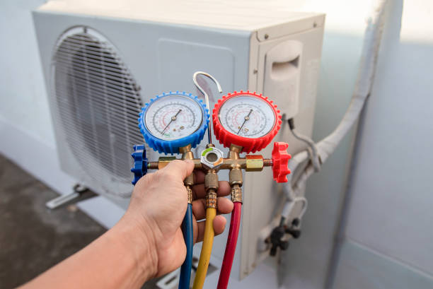 Technician checking pressure gauges on air conditioning unit