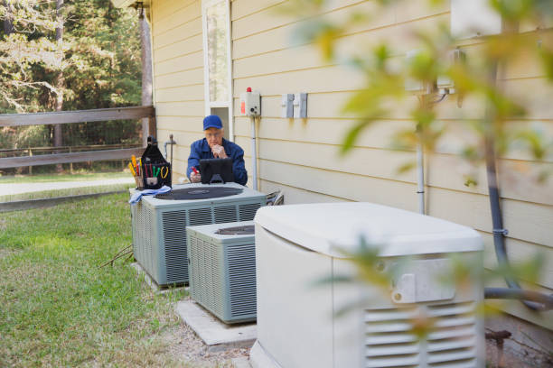 HVAC technician checking air conditioning units outside residential home