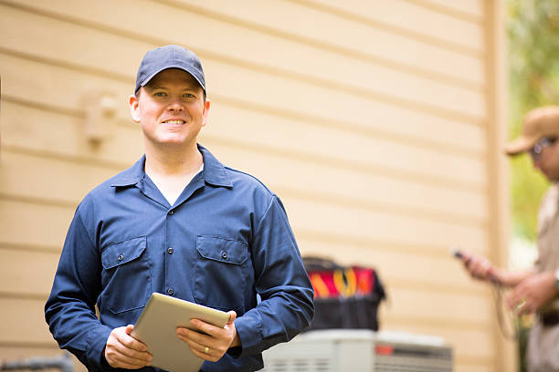 Smiling worker in blue uniform holding clipboard outside building