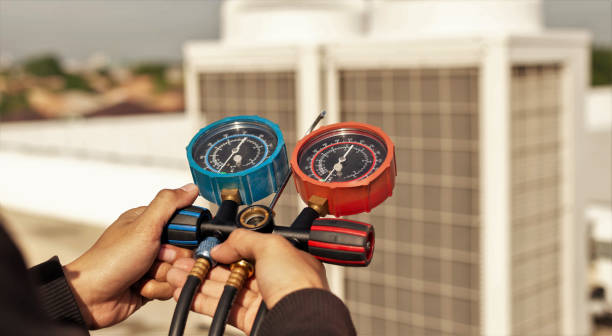 Technician holding blue and red pressure gauges for HVAC system